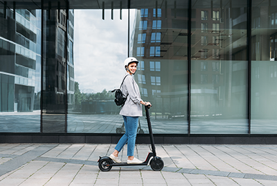 Une jeune femme sur une trottinette électrique portant un casque