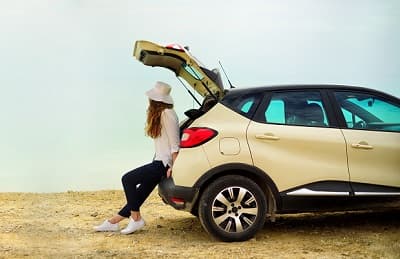 Femme appuyée contre sa voiture toit ouvert