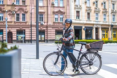 Une jeune femme qui pousse son vélo électrique sur un passage piéton