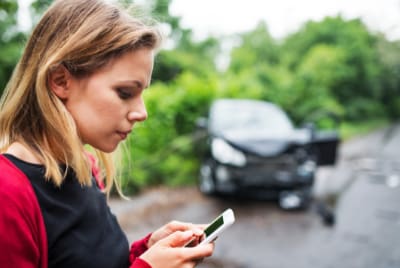 Une jeune femme avec son téléphone après un accident de voiture