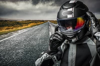 Motard enfilant son casque de moto sur la route