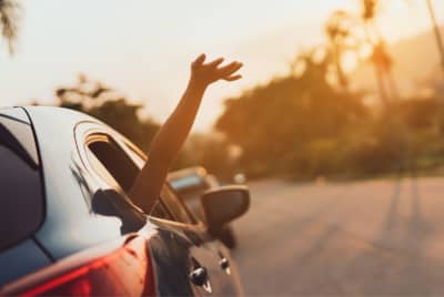 Une personne en voiture avec un bras qui sort par la fenêtre
