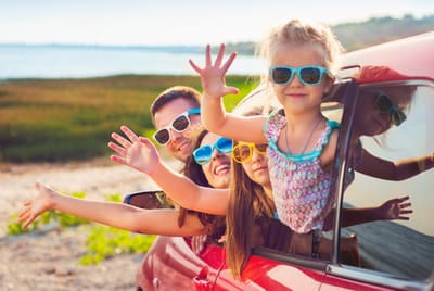Une famille en vacances faisant coucou à la fenêtre d'une voiture