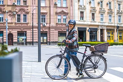 Une jeune femme portant un casque marchant à côté d'un vélo électrique