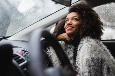 Femme à l'intérieur d'une voiture regardant la pluie
