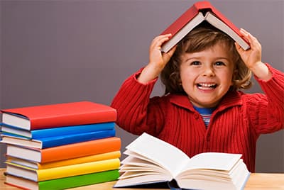 Un jeune garçon avec un libre ouvert posé sur sa tête