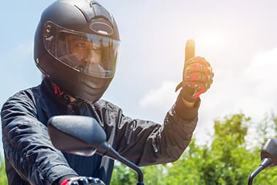 Un motard casqué levant le pouce en l'air