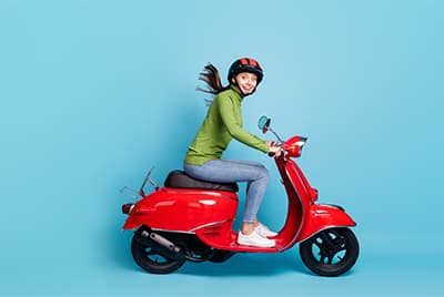Une jeune femme sur un scooter rouge sur fond bleu