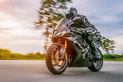 Motard qui circule à moto équipé d'un casque et d'une veste de protection