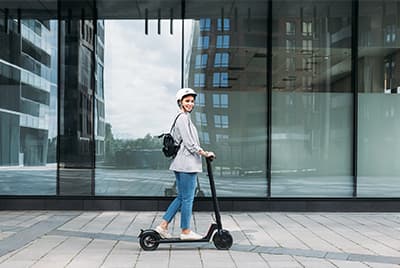 Une jeune femme avec un casque sur une trottinette électrique