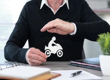 Un homme en pull entourant de ses mains une moto en image