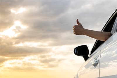 Un conducteur dans un voiture sortant son bras de la vitre baissée le pouce en l'air