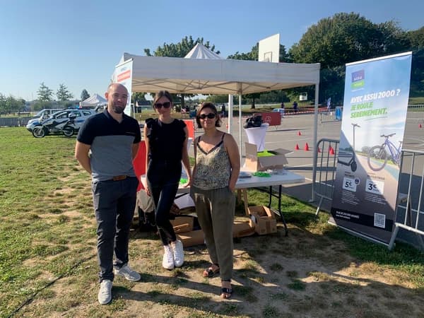 Deux femmes et un homme devant un stand
