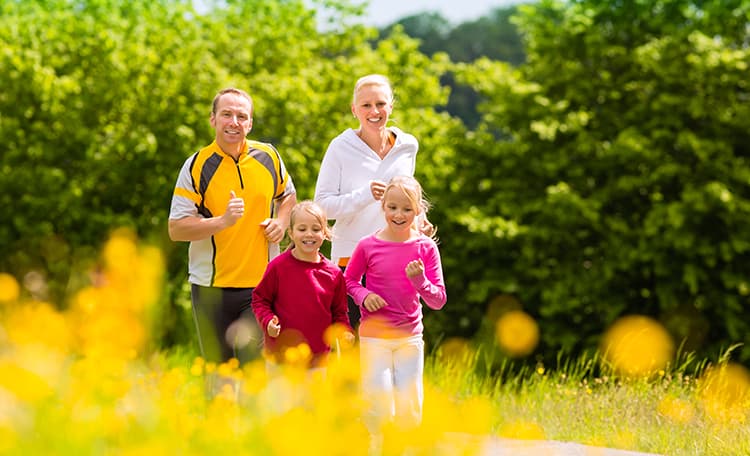 Un père et une mère qui courent avec leurs enfants dans la nature