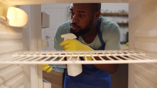 Vue de l'intérieur d'un frigo d'un homme nettoyant les étages du frigidaire