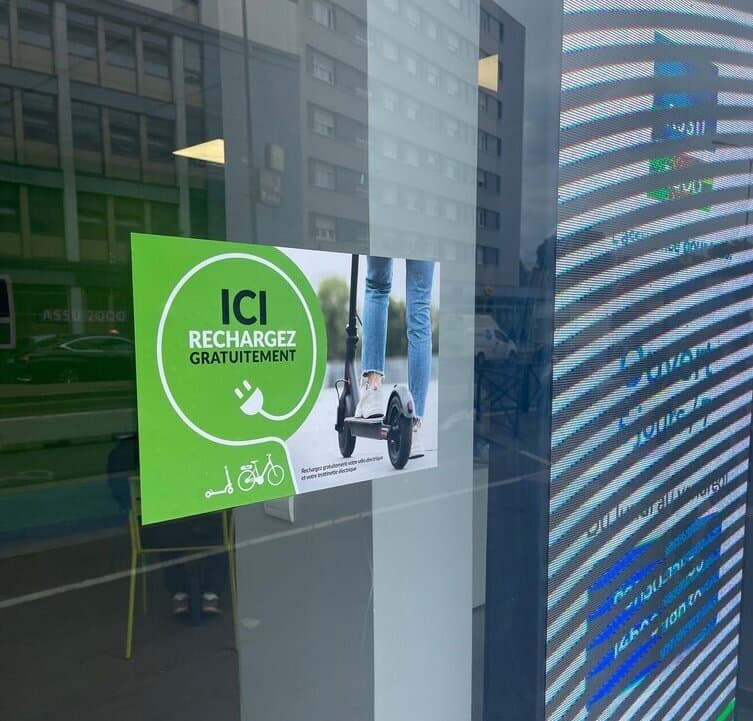 Affiche Ici rechargez gratuitement collée sur la vitrine d'une agence ASSU 2000