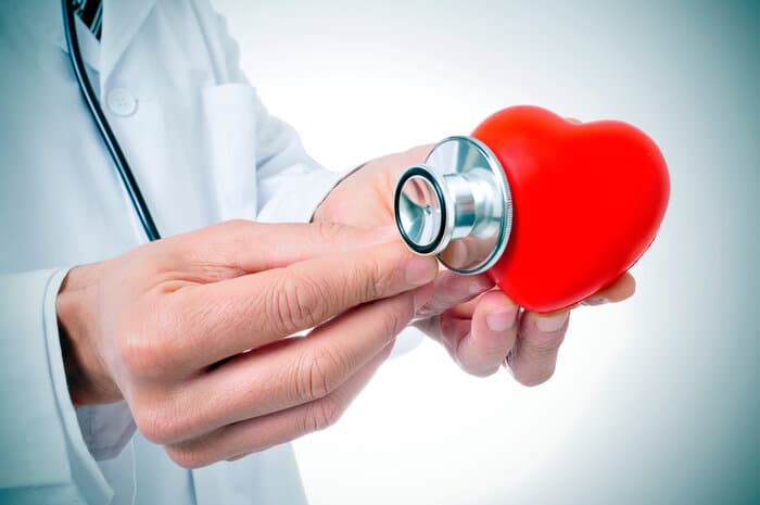 Un médecin avec un stéthoscope posé sur un coeur rouge