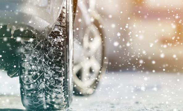 Une voiture équipée de pneus neige roulant sur une route enneigée