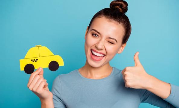 Une jeune femme pouce en l'air en tenant une voiture jaune miniature