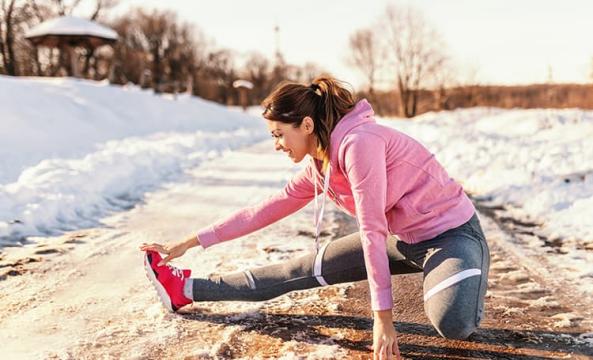 Une jeune femme s'étirant sur une route enneigée