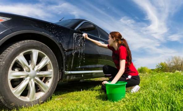 Jeune femme nettoyant sa voiture à l'extérieur