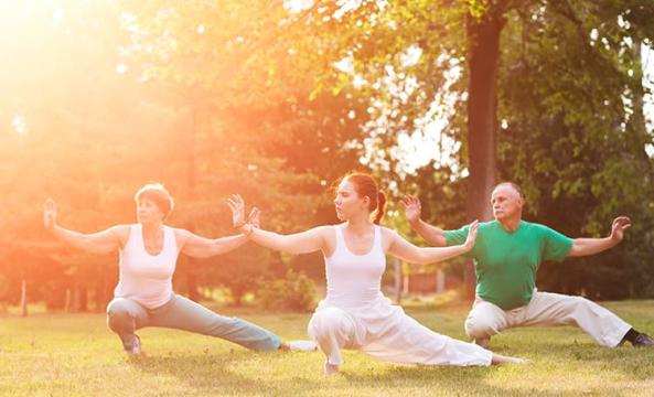 Trois personnes pratiquant le taï chi sur l'herbe