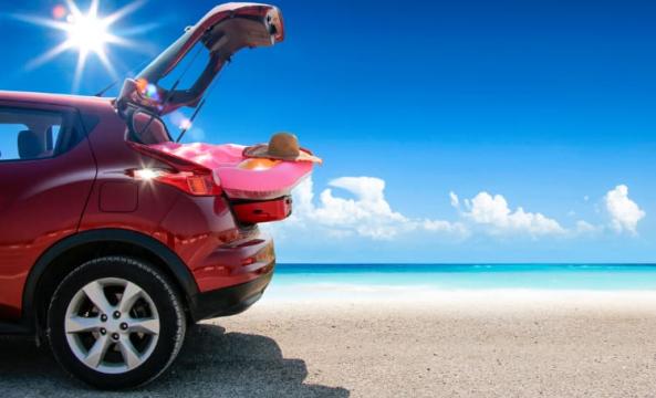 Voiture sur la plage, chargée de bagage pour la mer avec un beau soleil en fond