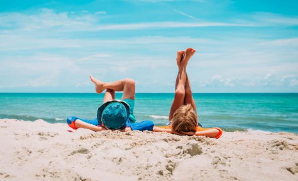 Deux enfants les pieds en l'air allongés sur la plage