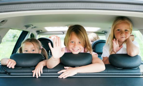 3 enfants souriants dans une voiture