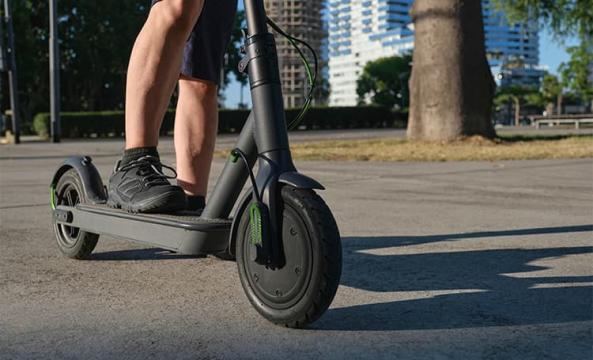 Gros plan sur les jambes d'un homme sur sa trottinette électrique