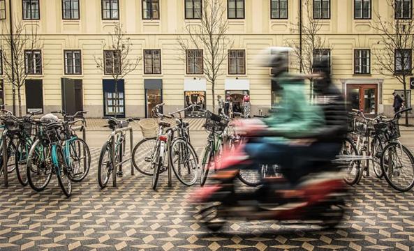 Des jeunes personnes floues sur un scooter rouge