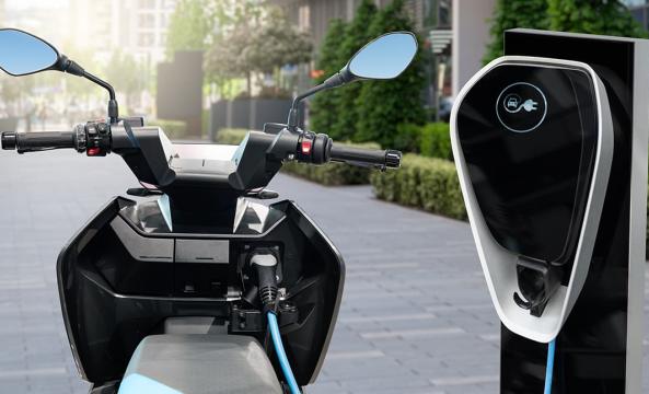 Un scooter électrique raccordé à une borne de recharge