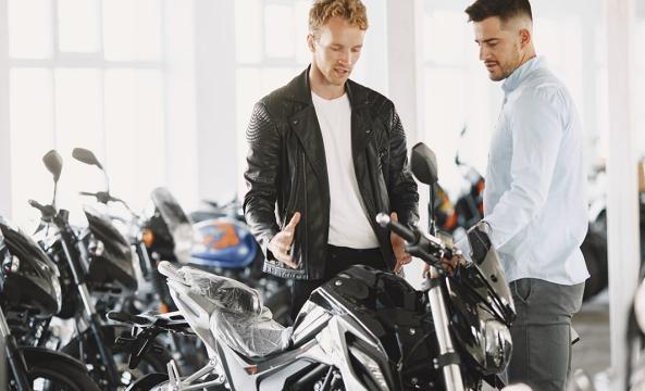 Un homme en blouson en cuir discutant avec un vendeur de motos