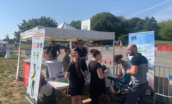 Un groupe de personnes devant le stand et le kakémono ASSU 2000