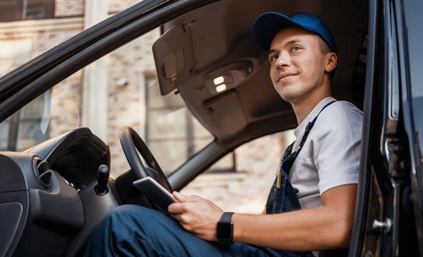 Un homme en salopette bleue de travail au volant de son véhicule professionnel