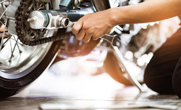 Un homme en train d'utiliser une clé mixte pour réparer sa moto