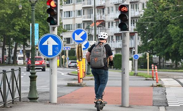Un homme casqué sur une trottinette électrique