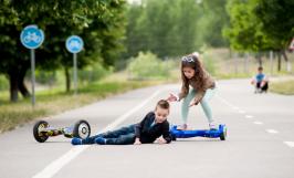 Deux enfants utilisant un hoverboard, l'un est par terre et l'autre vient l'aider