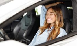 Jeune femme décontractée et souriante au volant de sa voiture