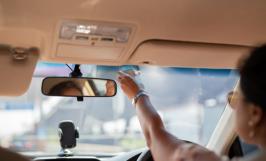 Une personne accrochant un badge de télépéage dans sa voiture