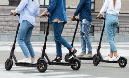 Quatre jeunes circulant en trottinettes électriques sur la route