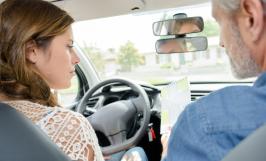Une jeune fille au volant d'une voiture à côté d'un moniteur d'auto-école