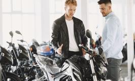 Un homme en blouson en cuir discutant avec un vendeur de motos
