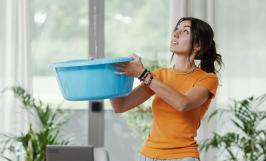 femme avec un seau d'eau suite à une fuite dans son appartement