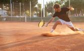 Un jeune homme jouant au tennis sur terre battue