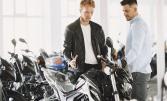 Un homme en blouson en cuir discutant avec un vendeur de motos