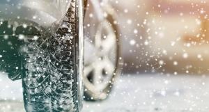 Une voiture équipée de pneus neige roulant sur une route enneigée