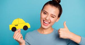 Une jeune femme pouce en l'air en tenant une voiture jaune miniature