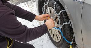 Un homme en train d'installer des chaines sur un pneu