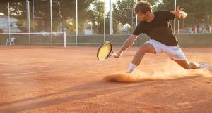 Un jeune homme jouant au tennis sur terre battue